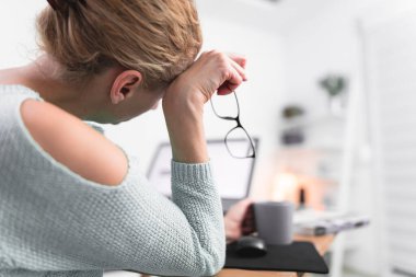 Kadın kendini iyi hissetmiyor, dizüstü bilgisayarla uğraşırken başı ağrıyor..