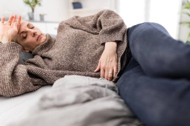 Evde mide sorunları olan yorgun bir kadın. Kanepede hasta ve hamile..