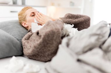 Yatakta hasta bir kadın, grip ve virüs enfeksiyonları, alerji, mevsimsel sağlık sorunları.