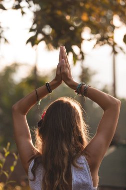 Arka planda turuncu güneş ışığıyla havada el ele tutuşan bir kadın..