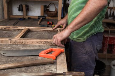 Erkek marangoz antika bir atölyede eski ahşap üzerinde çalışıyor..