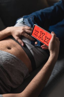 Modern akıllı telefon / cep telefonu tutan ve XX videoları izleyen bir adam. Maso hala modern çağda.