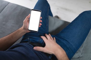 Modern akıllı telefon / cep telefonu ve kanepeye XXX videoları koyan bir adam. Maso hala modern çağda.
