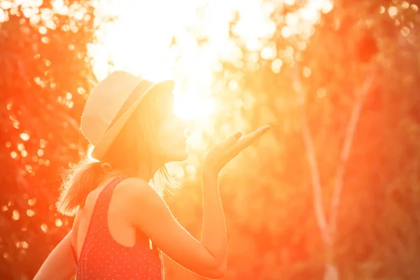 Woman blowing kiss and holding sun in forced perspective.