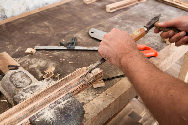 Male carpenter working on old wood in a retro vintage workshop.