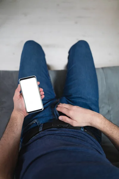 Man holding modern smartphone / cellphone and watching XX videos on a home couch. Taboo still in modern times.