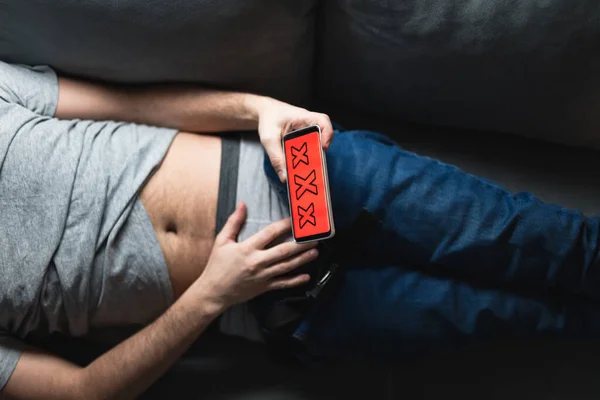 Homem Segurando Smartphone Celular Moderno Assistindo Vídeos Sofá Casa Tabu — Fotografia de Stock