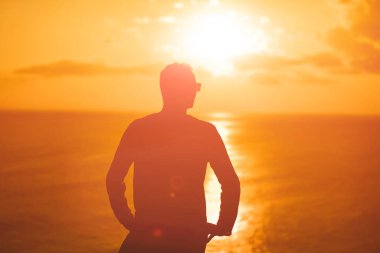 Okyanusun üzerindeki adada tropik yaz günbatımına sahip bir adam..