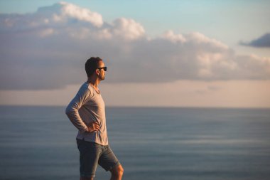 Okyanusun üzerindeki adada tropik yaz günbatımına sahip bir adam..