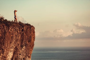 Okyanusun yukarısındaki kayalıklarda tropikal yaz günlerinin tadını çıkaran bir kadın..