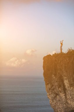 Okyanusun yukarısındaki kayalıklarda tropikal yaz günlerinin tadını çıkaran bir kadın..