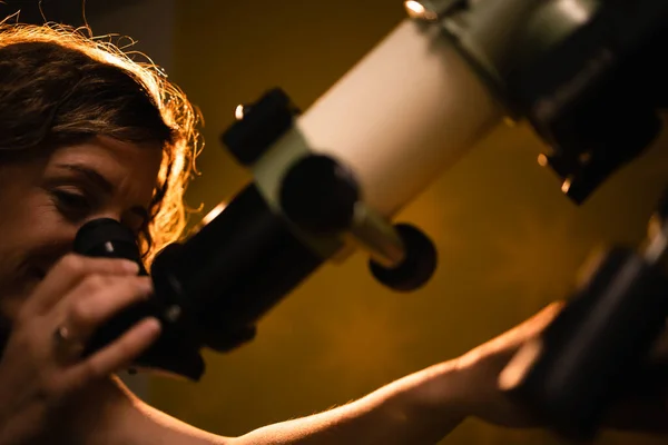 Woman looking at the stars through a telescope- astrology concept, horoscope predictions about the future.