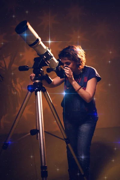 Pregnant woman looking at the stars through a telescope- astrology concept, horoscope predictions about the baby.