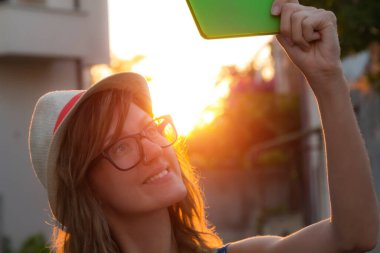 Sevimli genç kadın sokakta cep telefonu kullanarak.