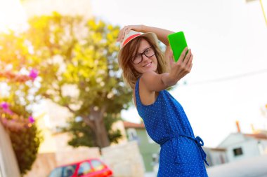 Sevimli genç kadın sokakta cep telefonu kullanarak.