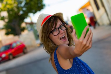 Sevimli genç kadın sokakta cep telefonu kullanarak.