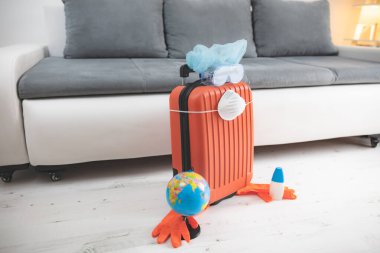 İçinde toprak küresi, eldiven, maske ve grip virüslerinden korunan bir valiz. 2020 'de tüm dünyayı gezen turistler iptal edildi..