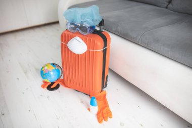 İçinde toprak küresi, eldiven, maske ve grip virüslerinden korunan bir valiz. 2020 'de tüm dünyayı gezen turistler iptal edildi..