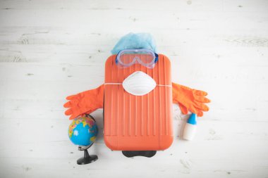 İçinde toprak küresi, eldiven, maske ve grip virüslerinden korunan bir valiz. 2020 'de tüm dünyayı gezen turistler iptal edildi..