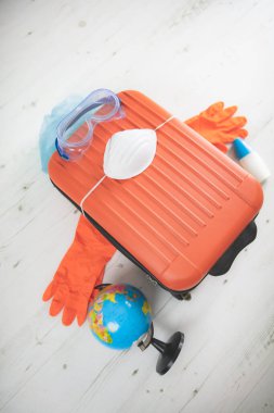 İçinde toprak küresi, eldiven, maske ve grip virüslerinden korunan bir valiz. 2020 'de tüm dünyayı gezen turistler iptal edildi..