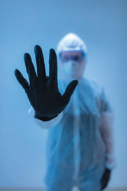 Tıbbi doktor, virüslerden ve hastalıklardan korunmak için giyinmiş bilim adamı elinde dur işareti tutuyor- virüsün yayılmasını engelle.