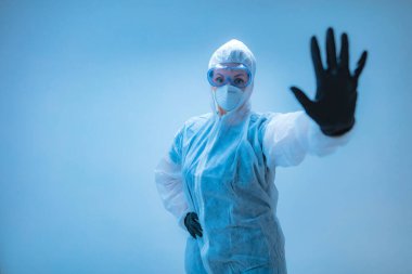 Tıbbi doktor, virüslerden ve hastalıklardan korunmak için giyinmiş bilim adamı elinde dur işareti tutuyor- virüsün yayılmasını engelle.