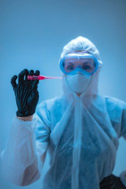 Tıbbi doktor, vücut ısısını ölçmek için termometre tutan virüslerden ve hastalıklardan korunmak için giysi giyen bilim adamı..