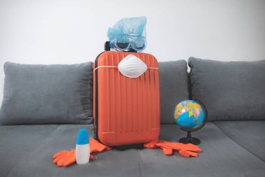 İçinde toprak küresi, eldiven, maske ve grip virüslerinden korunan bir valiz. 2020 'de tüm dünyayı gezen turistler iptal edildi..