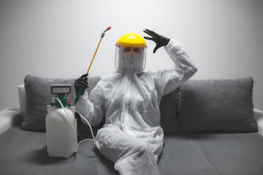 Koruyucu antiviral maskeli kişi, kimyasal dezenfekte spreyi şişesi ev izolasyonunda..