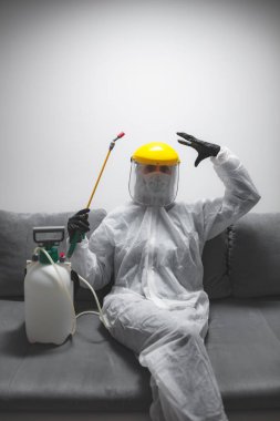 Koruyucu antiviral maskeli kişi, kimyasal dezenfekte spreyi şişesi ev izolasyonunda..
