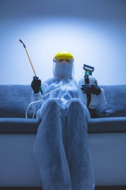 Koruyucu antiviral maskeli kişi, kimyasal dezenfekte spreyi şişesi ev izolasyonunda..