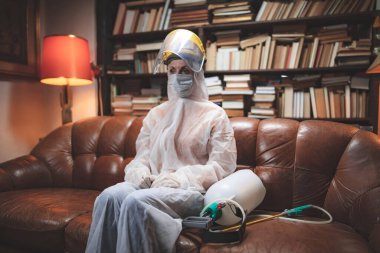 Koruyucu antiviral maskeli kişi, kimyasal dezenfekte spreyi şişesi ev izolasyonunda..
