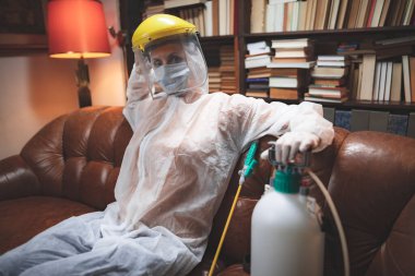 Koruyucu antiviral maskeli kişi, kimyasal dezenfekte spreyi şişesi ev izolasyonunda..