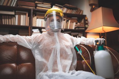 Koruyucu antiviral maskeli kişi, kimyasal dezenfekte spreyi şişesi ev izolasyonunda..