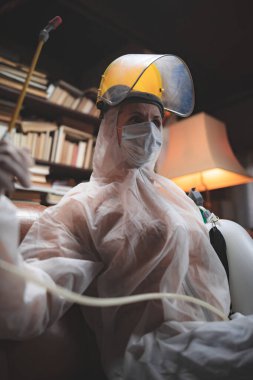 Koruyucu antiviral maskeli kişi, kimyasal dezenfekte spreyi şişesi ev izolasyonunda..