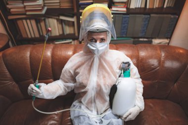 Koruyucu antiviral maskeli kişi, kimyasal dezenfekte spreyi şişesi ev izolasyonunda..