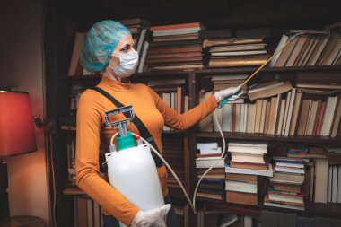 Koruyucu antiviral maskeli kadın, kimyasal dezenfekte spreyi şişesi ev izolasyonunda..