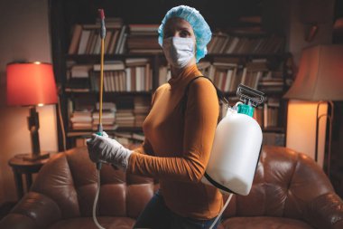 Koruyucu antiviral maskeli kadın, kimyasal dezenfekte spreyi şişesi ev izolasyonunda..