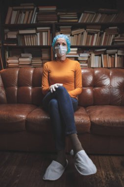 Koruyucu antiviral maskeli bir kadın izolasyon ve karantinada evde oturuyor..