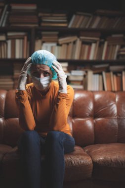 Koruyucu antiviral maskeli bir kadın izolasyon ve karantinada evde oturuyor..