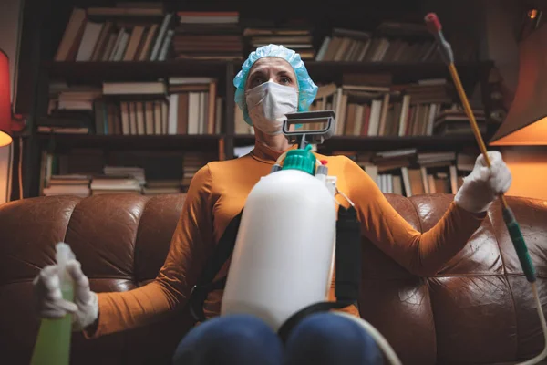 Koruyucu antiviral maskeli kadın, kimyasal dezenfekte spreyi şişesi ev izolasyonunda..
