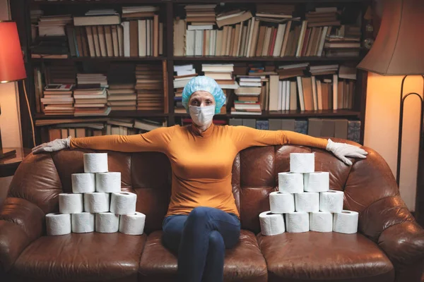 Woman with protective antiviral mask and a reserve of toilet paper waiting anxious in home isolation.