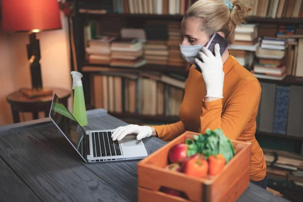 携带防毒面具的妇女在家中使用笔记本电脑 在网上订购食物 食品和用品 以防止感染病毒和病原体 — 图库照片
