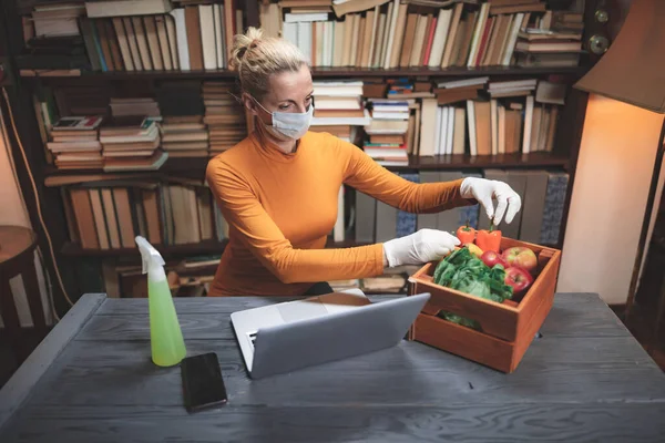 带防护口罩的妇女在网上订购的食物上喷洒灭菌化学品 — 图库照片