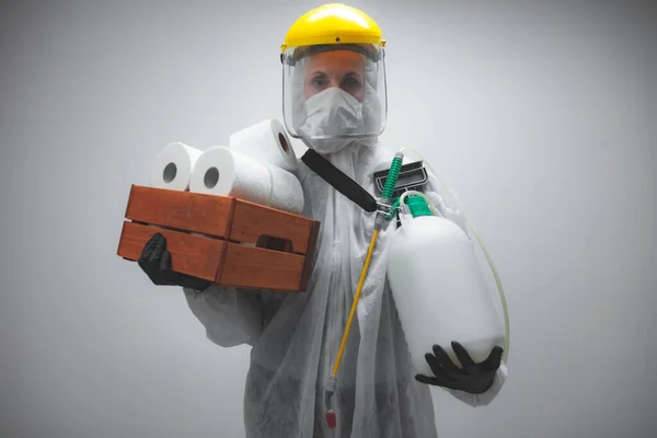 保護スーツとフェイスマスクを持つ人科学者 ウイルス 細菌に対する除染のためのバイオハザードスプレー 家庭でのトイレットペーパーのストックのパラノイア 日の終わりを待っている — ストック写真