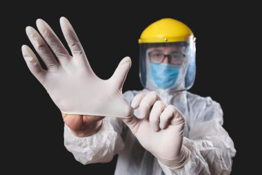 Tıp doktoru, hemşire, cerrah, koruyucu maske, gözlük ve eldivenlerle çalışan psikolog panik, salgın ve siyah arka planda çekim yapan insanlara yardım ediyor..