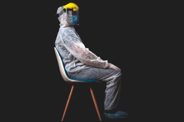 Tıp doktoru, hemşire, cerrah, koruyucu maske, gözlük ve eldivenlerle çalışan psikolog panik, salgın ve siyah arka planda çekim yapan insanlara yardım ediyor..