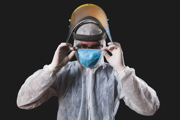 Medical doctor, nurse, surgeon, psychologist working with protective mask, glasses and gloves helping people in the days of panic, pandemic - studio shot on black background.