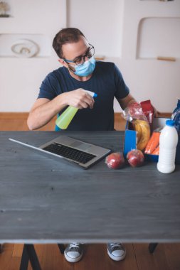 Dünya çapındaki virüs salgını sırasında internetten sipariş edilen yiyecekleri sterilize eden satıcı. Alışveriş / satın alma / sipariş alışverişi ve uzaktan bilgisayar ve internet kullanarak yiyecek.