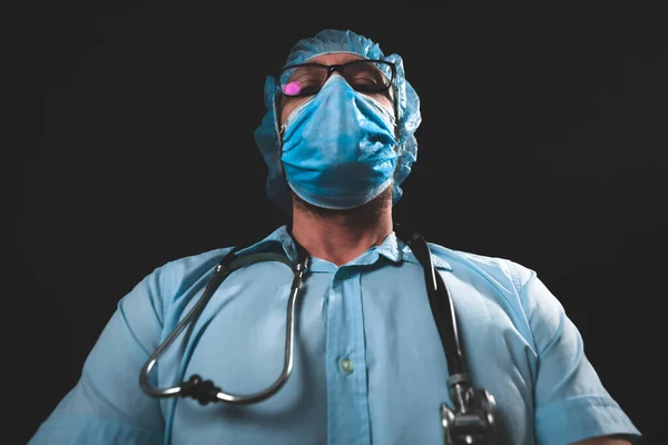 Medical doctor, nurse, surgeon, psychologist working with protective mask, glasses and gloves helping people in the days of panic, pandemic - studio shot on black background.